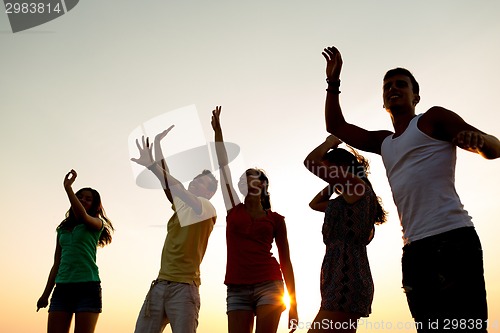 Image of smiling friends dancing on summer beach