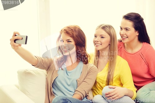 Image of smiling teenage girls with smartphone at home