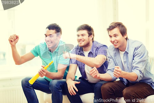 Image of happy male friends with vuvuzela watching sports