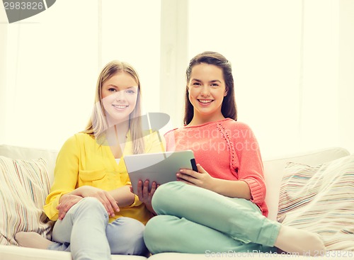 Image of two smiling teenage girls with tablet pc at home