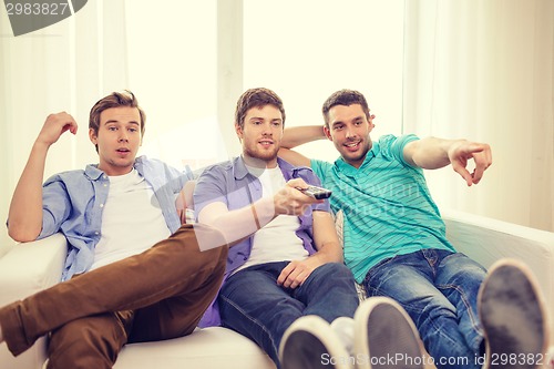 Image of smiling friends with remote control at home