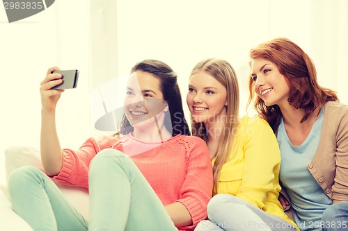 Image of smiling teenage girls with smartphone at home