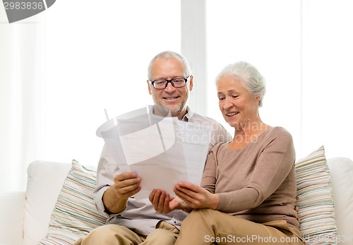 Image of happy senior couple with papers at home