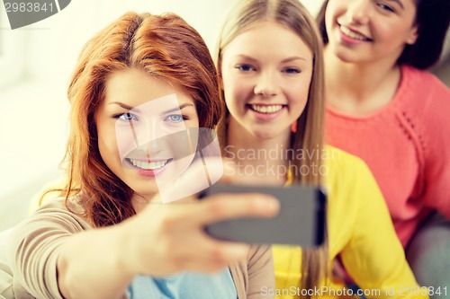 Image of smiling teenage girls with smartphone at home