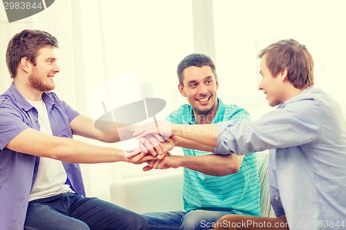 Image of smiling male friends with hands together at home