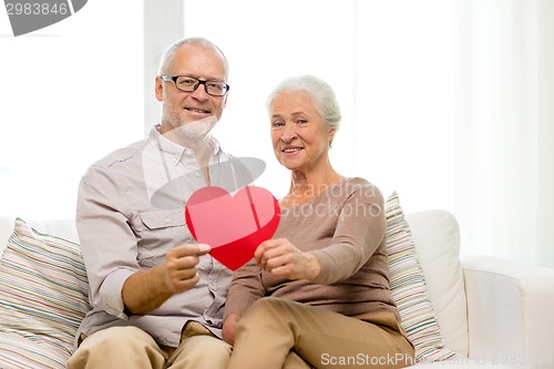 Image of happy senior couple with red heart shape at home