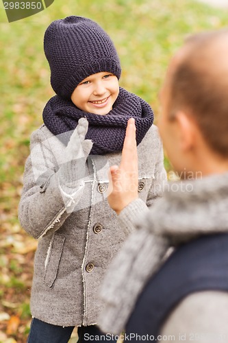 Image of happy father and son making high five in park