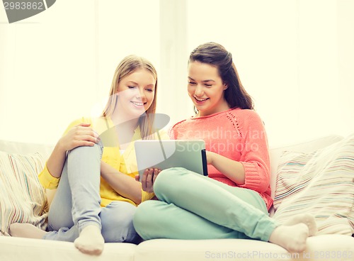 Image of two smiling teenage girls with tablet pc at home