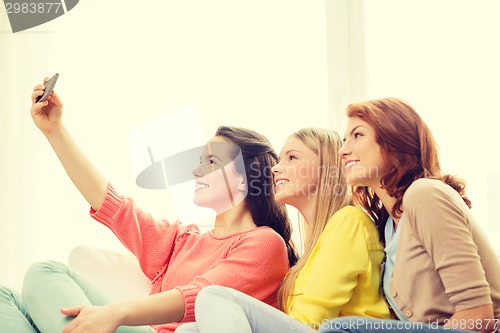 Image of smiling teenage girls with smartphone at home