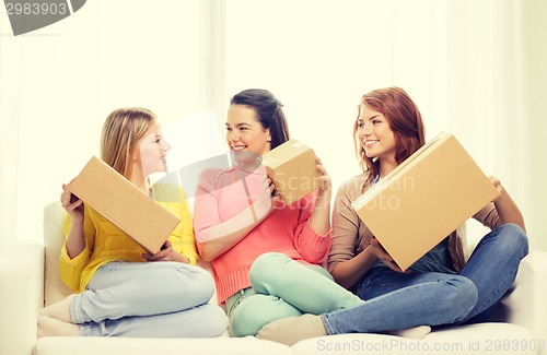 Image of smiling teenage girls with cardboard boxes at home