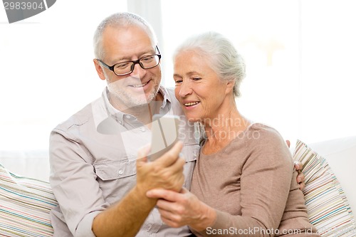 Image of happy senior couple with smartphone at home