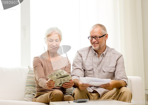 Image of senior couple with money and calculator at home