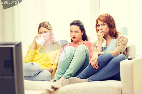 Image of three sad teenage girl watching tv at home