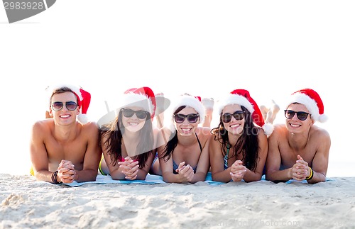 Image of group of friends in santa helper hats on beach