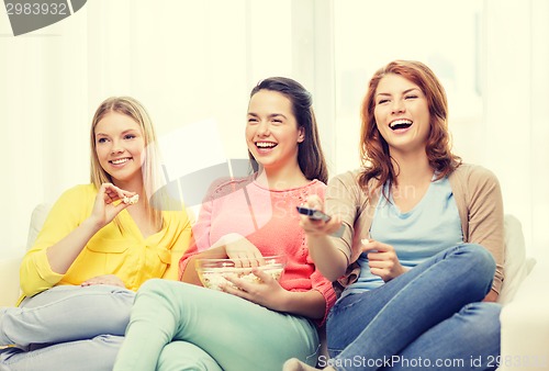 Image of three smiling teenage girl watching tv at home