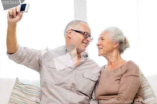 Image of happy senior couple with camera at home