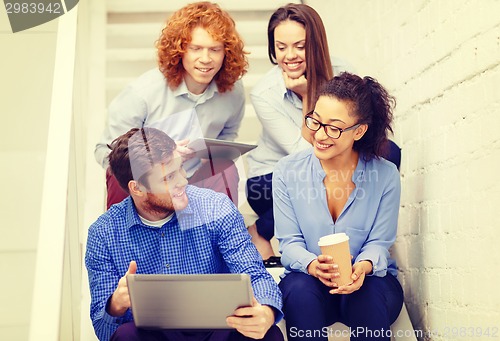 Image of team with laptop and tablet pc on staircase