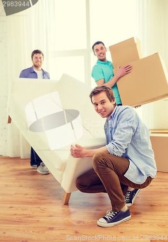 Image of smiling friends with sofa and boxes at new home