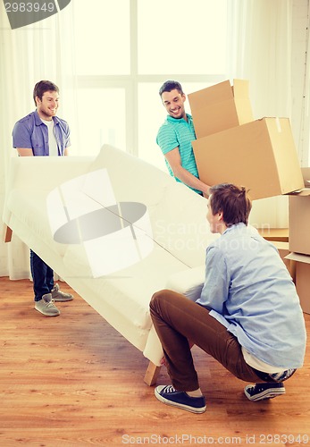 Image of smiling friends with sofa and boxes at new home