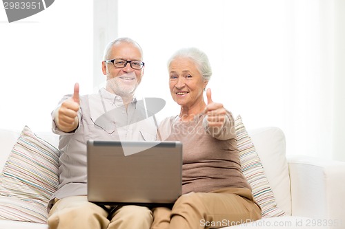Image of happy senior couple with laptop at home
