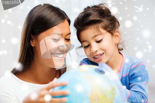 Image of mother and daughter with globe indoors