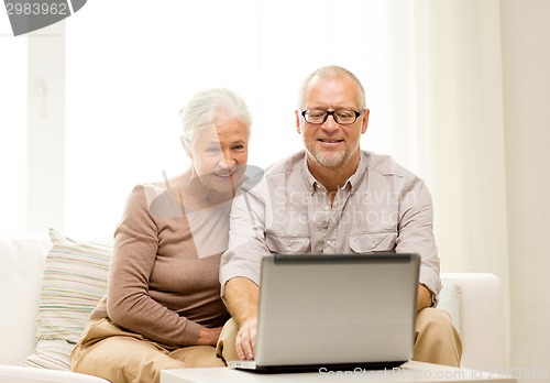 Image of happy senior couple with laptop at home