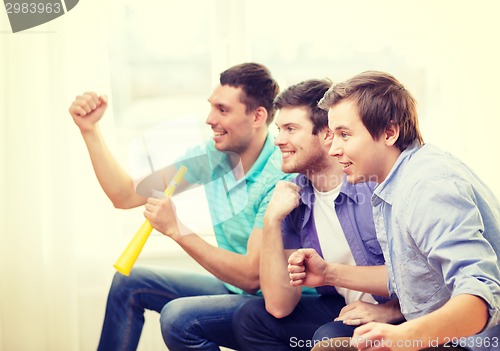 Image of happy male friends with vuvuzela watching sports