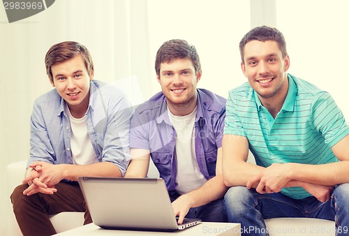 Image of smiling friends with laptop computer at home