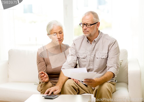 Image of senior couple with papers and calculator at home