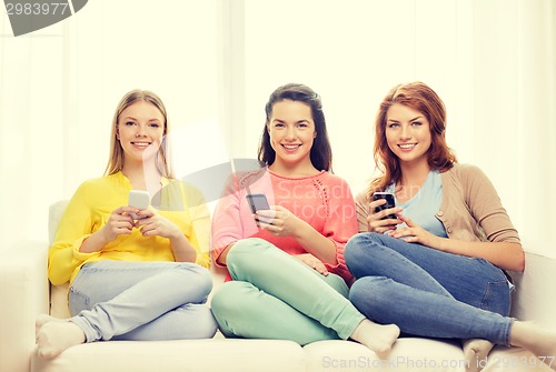 Image of smiling teenage girls with smartphones at home