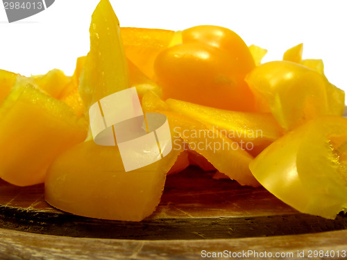 Image of Slitted yellow pepper on brown wooden plate