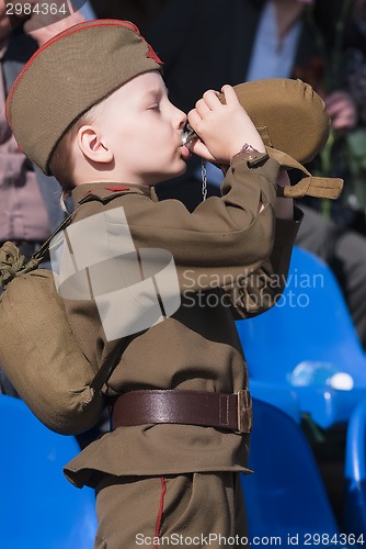 Image of Young boy in World War 2 uniform drinks water