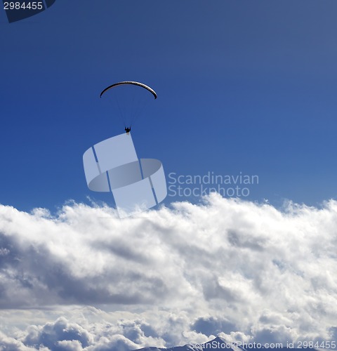 Image of Silhouette of paraglider and blue sun sky