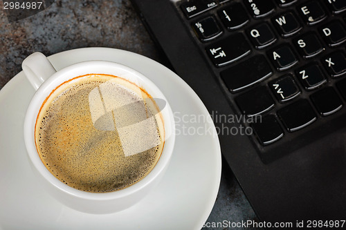 Image of Closeup shot of cup of coffee and kayboard