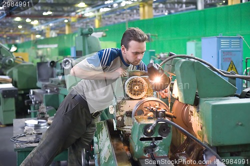 Image of Young turner adjusts machine