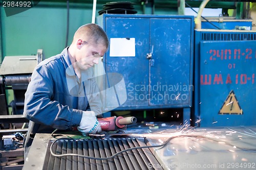 Image of Young worker grinding door