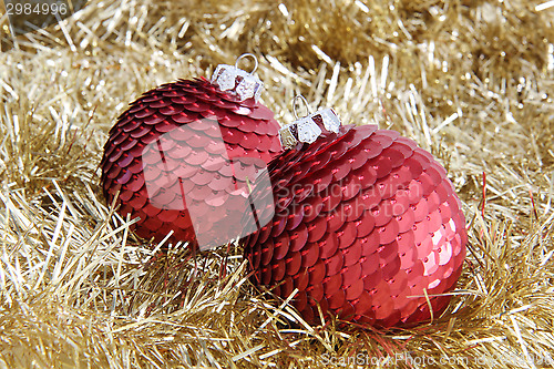 Image of Two red Christmas baubles on golden tinsel