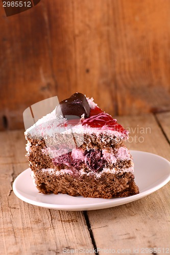 Image of Piece of cake with chocolate heart on wooden background