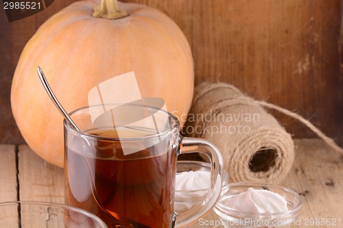 Image of Cup of tea with autumn leaves with pumpkin on wooden table