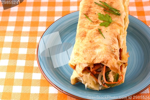 Image of burrito with tomatoes and cheese on blue plate