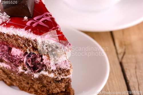 Image of Piece of chocolate cake and white slice on wooden background