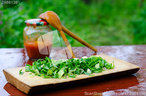 Image of Chopped green onions on a cutting Board, on the background of tw