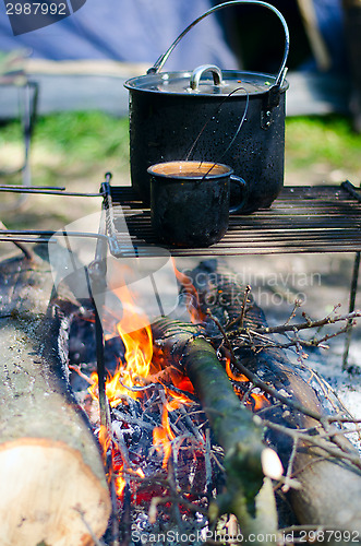 Image of Tourist boiler with food and a mug with water on a fire