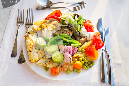 Image of Meat, fish and various vegetable garnish on a plate.