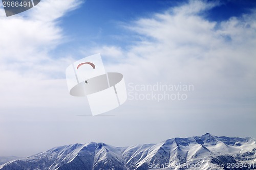 Image of Paraglider silhouette of mountains in windy sky