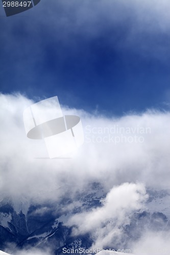 Image of Snowy mountains in clouds at sun day