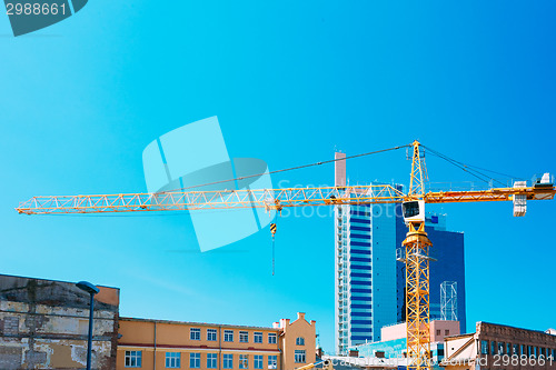 Image of Construction Crane On Background Of New Modern Skyscraper And Ol