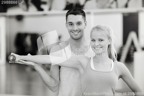 Image of male trainer with woman working out with dumbbell