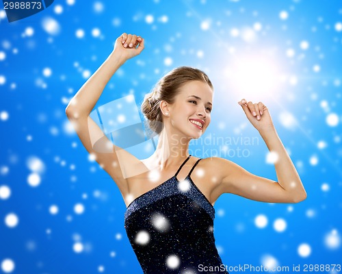 Image of smiling woman dancing with raised hands