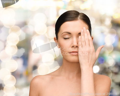 Image of smiling young woman covering face with hand